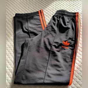 Adidas track pants with orange stripes and logo.
